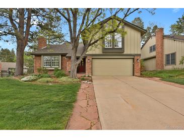 Charming two-story home boasts a manicured lawn, brick accents, and attached two car garage at 7882 S Valentia Way, Centennial, CO 80112