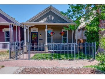 Charming home featuring a manicured lawn, a decorative fence, and hanging floral arrangements at 2941 Glenarm Pl, Denver, CO 80205