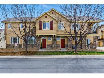 Inviting townhomes with stone accents, red doors, bare trees, and well-maintained landscaping create a charming curb appeal at 9980 W Jewell Ave # B, Lakewood, CO 80232