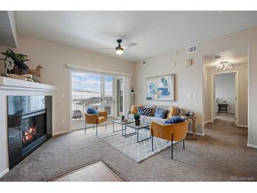 Bright living room with fireplace, balcony access, and stylish furniture at 15700 E Jamison Dr # 7-205, Englewood, CO 80112