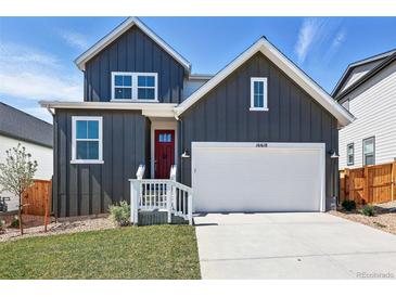 Charming two-story home features a red door, white garage, and modern architectural design at 16618 W 92Nd Pl, Arvada, CO 80007