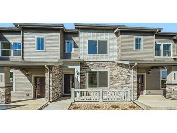 Charming townhome showcases stone accents, gray siding, covered porch, and well-maintained landscaping at 1954 S Haleyville Way, Aurora, CO 80018