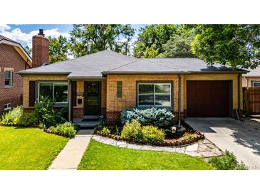 Charming brick home featuring a well-manicured lawn and colorful landscaping at 1635 Poplar St, Denver, CO 80220