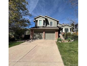 Charming two-story home featuring a brick facade and a two-car garage with a concrete driveway at 11245 San Joaquin Rdg, Littleton, CO 80127