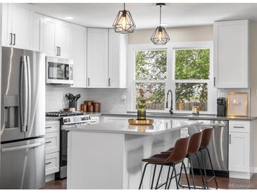 Modern kitchen with white cabinets, stainless steel appliances, and a stylish island with seating at 9220 Yucca Way, Thornton, CO 80229