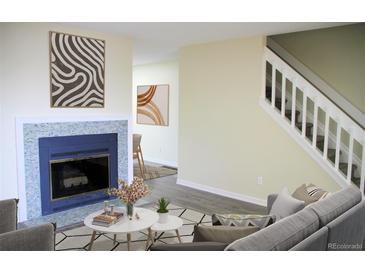 Cozy living room featuring a fireplace with blue tile surround, modern decor, and staircase at 11638 Community Center Dr # 20, Northglenn, CO 80233