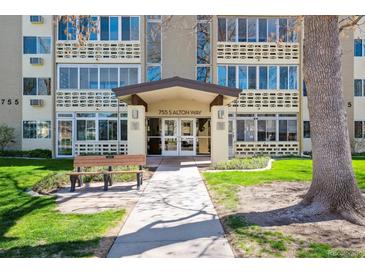 Condo building entrance with a walkway, bench, and well-maintained landscaping at 755 S Alton Way # 8D, Denver, CO 80247
