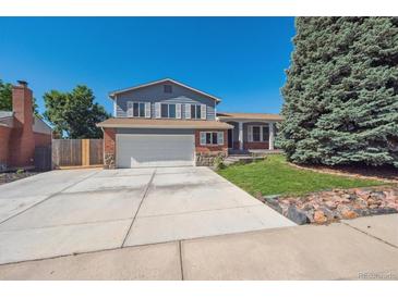 Two-story home with blue siding, brick accents, a two-car garage, and mature landscaping at 9442 W Walden Ave, Littleton, CO 80128