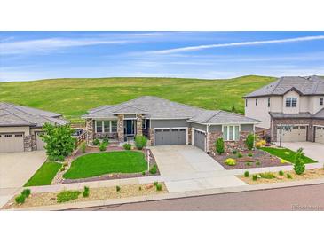Beautiful single-Gathering home featuring a three-car garage and manicured landscaping with natural backdrop at 9433 Torrey Way, Arvada, CO 80007