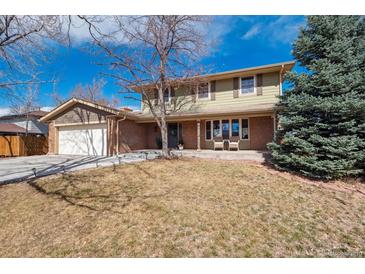 Charming two-story home featuring a brick facade, covered porch with seating, mature trees, and attached two-car garage at 4179 E Peakview Cir, Centennial, CO 80121