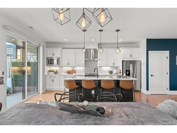 Modern kitchen boasts an island with seating, stainless steel appliances, and stylish pendant lighting at 5240 N Raleigh St, Denver, CO 80212