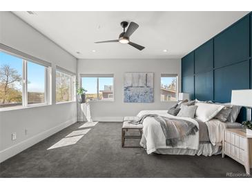 Sun-filled main bedroom featuring a ceiling fan, gray carpet, and modern decor at 5240 N Raleigh St, Denver, CO 80212