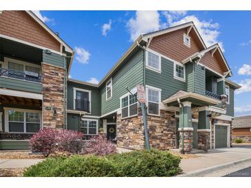 Beautiful townhome with green siding, stone accents, and well-maintained landscaping, creating inviting curb appeal at 7080 Simms St # 105, Arvada, CO 80004