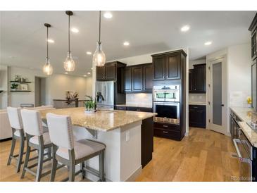 A chef's kitchen features a large island, granite counters, and modern stainless steel appliances at 17637 W 87Th Ave, Arvada, CO 80007
