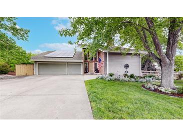 Charming home featuring a well-manicured lawn, mature trees, and a welcoming driveway leading to a spacious garage at 7567 Parkview Mtn, Littleton, CO 80127