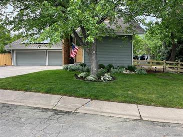 Charming home featuring a well-manicured lawn, mature trees, a two-car garage, and a welcoming front entrance at 7567 Parkview Mtn, Littleton, CO 80127