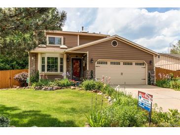 Charming two-story home with a well-maintained lawn and colorful landscaping, a two car garage, and stone accents at 6687 Devinney Ct, Arvada, CO 80004
