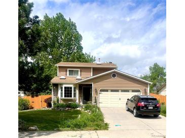 Charming two-story home features a manicured lawn, two car garage, and beautiful landscaping at 6687 Devinney Ct, Arvada, CO 80004