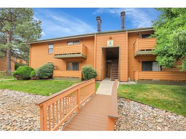 Charming condo exterior featuring a well-maintained lawn and wooden bridge entrance at 3335 S Ammons St # 6-105, Lakewood, CO 80227