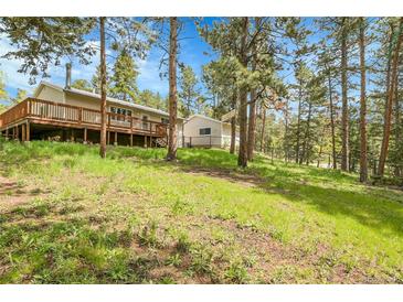 Charming home featuring a spacious deck and surrounded by lush greenery and tall trees at 26752 Vosler St, Conifer, CO 80433