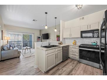 Modern kitchen with granite countertops and stainless steel appliances that opens to the living room at 8435 Pebble Creek Way # 104, Highlands Ranch, CO 80126