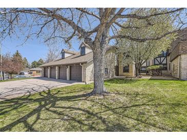 Residential garages attached to tan brick condominium with manicured green grass lawn at 4250 S Olive St # 102, Denver, CO 80237