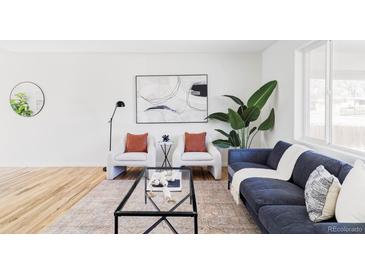 Bright living room featuring a stylish blue sofa, modern decor, and large windows at 8651 Franklin St, Denver, CO 80229