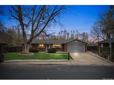Charming brick home with a well-manicured lawn and mature landscaping at twilight at 6609 W Mexico Pl, Lakewood, CO 80232