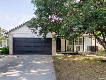 Charming single-story home with a dark two-car garage and a welcoming front porch at 14608 E 52Nd Ave, Denver, CO 80239