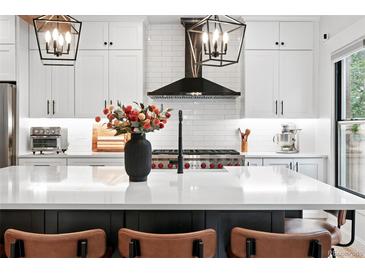 Modern kitchen boasts a large island, updated appliances, and stylish black accents at 3008 N York St, Denver, CO 80205