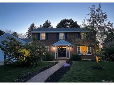 Charming brick home featuring a walkway to the front door, set amongst a well-manicured lawn at 6953 S Prescott St, Littleton, CO 80120