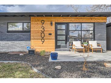 Inviting front entrance with modern wood accents, black framed windows, and cozy outdoor seating at 9309 Highland Pl, Arvada, CO 80002