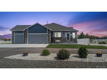 Ranch-style home with three-car garage, landscaping, and a charming front porch at 10610 E 167Th Pl, Brighton, CO 80602