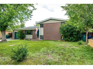 Charming two-story home featuring a brick facade, lush lawn, and mature trees at 3111 Troy St, Aurora, CO 80011