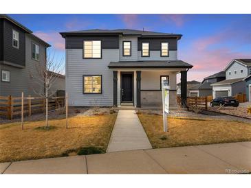 Charming two-story home featuring a covered front porch and modern gray and white color scheme at 10661 Reunion Pkwy, Commerce City, CO 80022