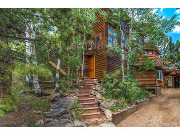 Charming cabin-style home with wood siding and inviting stone staircase surrounded by lush trees at 1575 York Gulch Rd, Idaho Springs, CO 80452