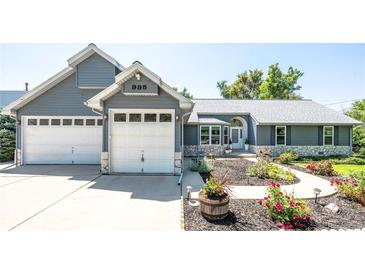 Charming gray house boasts an attached 2-car garage and a walkway with flowers in the front yard at 995 Chase St, Lakewood, CO 80214