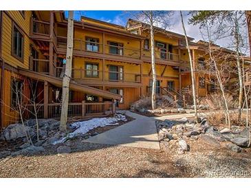 Multi-level condo with wooden balconies, natural landscaping, and a stone walkway leading to the entrance at 820 Columbine Rd # 10, Breckenridge, CO 80424