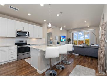 Bright eat-in kitchen featuring white cabinets, stainless steel appliances, and breakfast bar seating that overlooks the living area at 420 E Fremont Pl # 309, Centennial, CO 80122
