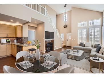 Open-concept living space with a fireplace, connecting the living room, dining area, and kitchen at 8300 Fairmount Dr # J105, Denver, CO 80247