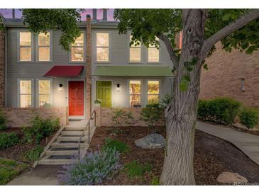 Charming townhome exterior featuring colorful awnings, a brick facade, and a landscaped front yard at dusk at 1150 Inca St # 43, Denver, CO 80204