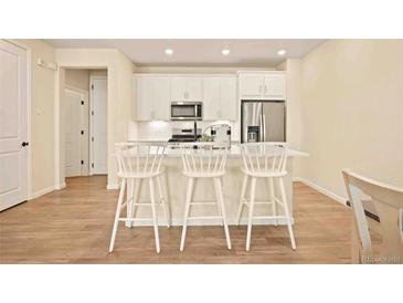 Modern kitchen with white cabinetry, stainless steel appliances, and breakfast bar with seating at 8055 Navajo River Loop # B, Littleton, CO 80125
