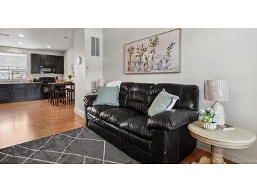 Living room features a dark leather sofa, hardwood floors and modern decor at 8187 Martin Luther King Blvd, Denver, CO 80238