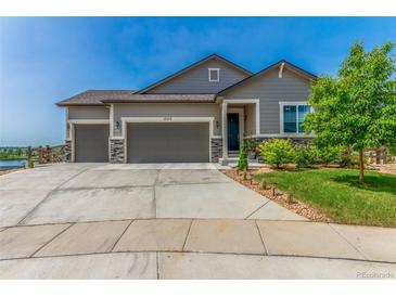 Charming home featuring a three-car garage and well-manicured lawn with a stone-accented facade at 12513 Shore Point St, Firestone, CO 80504