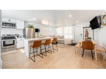 Open concept living space with modern kitchen island, comfortable seating, and dining area, all bathed in natural light at 7450 Granada Rd, Denver, CO 80221