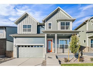 Charming two-story home featuring a two-car garage and a welcoming porch with a vibrant orange door at 21097 E 62Nd Dr, Aurora, CO 80019