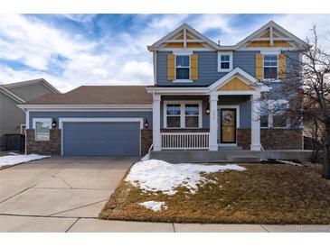 Charming two-story home with a covered porch, stone accents, and a two-car garage at 15415 Carob Cir, Parker, CO 80134