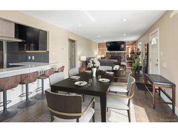 Inviting dining room with seating for six, flowing into a living room with a stone fireplace feature at 7669 Pecos St, Denver, CO 80221