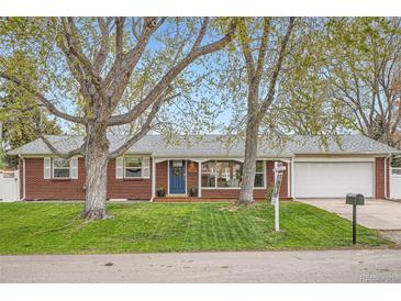 Charming red brick ranch with a blue front door, lush lawn, and mature trees in a desirable neighborhood at 9580 W 12Th Pl, Lakewood, CO 80215