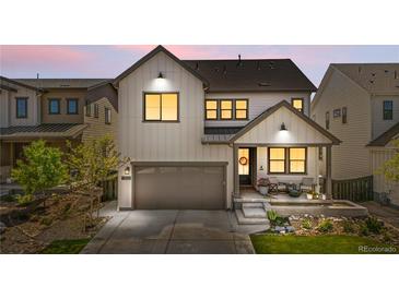 Charming two-story home with landscaped front yard, covered porch, and attached two car garage during sunset at 9140 Moondance Sw Dr, Littleton, CO 80125
